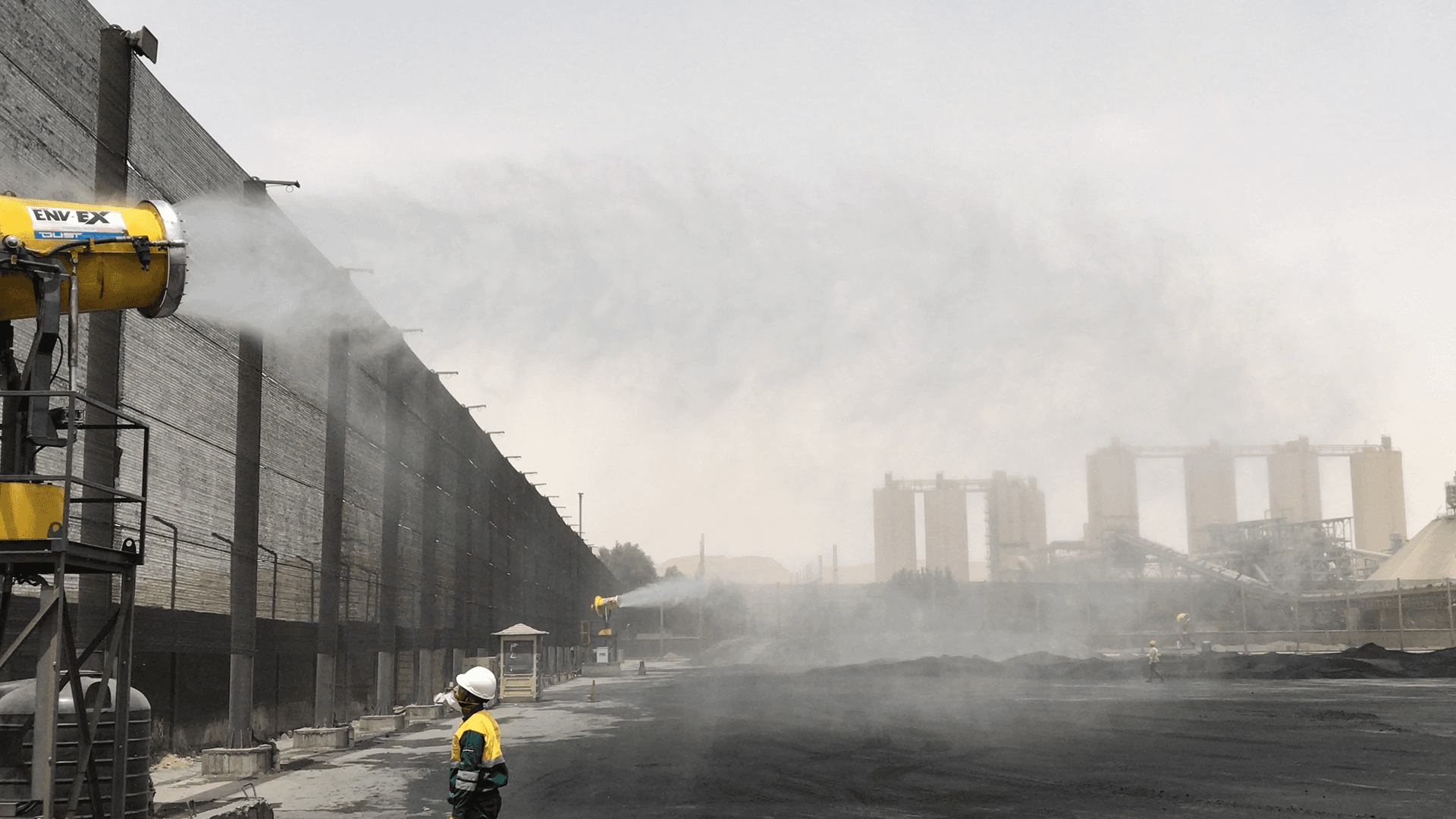 A dust suppression system operating near a conveyor belt transfer point.