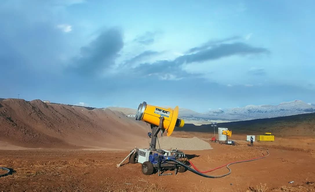 A trailer-mounted dust control system with a large water tank at a mining quarry.