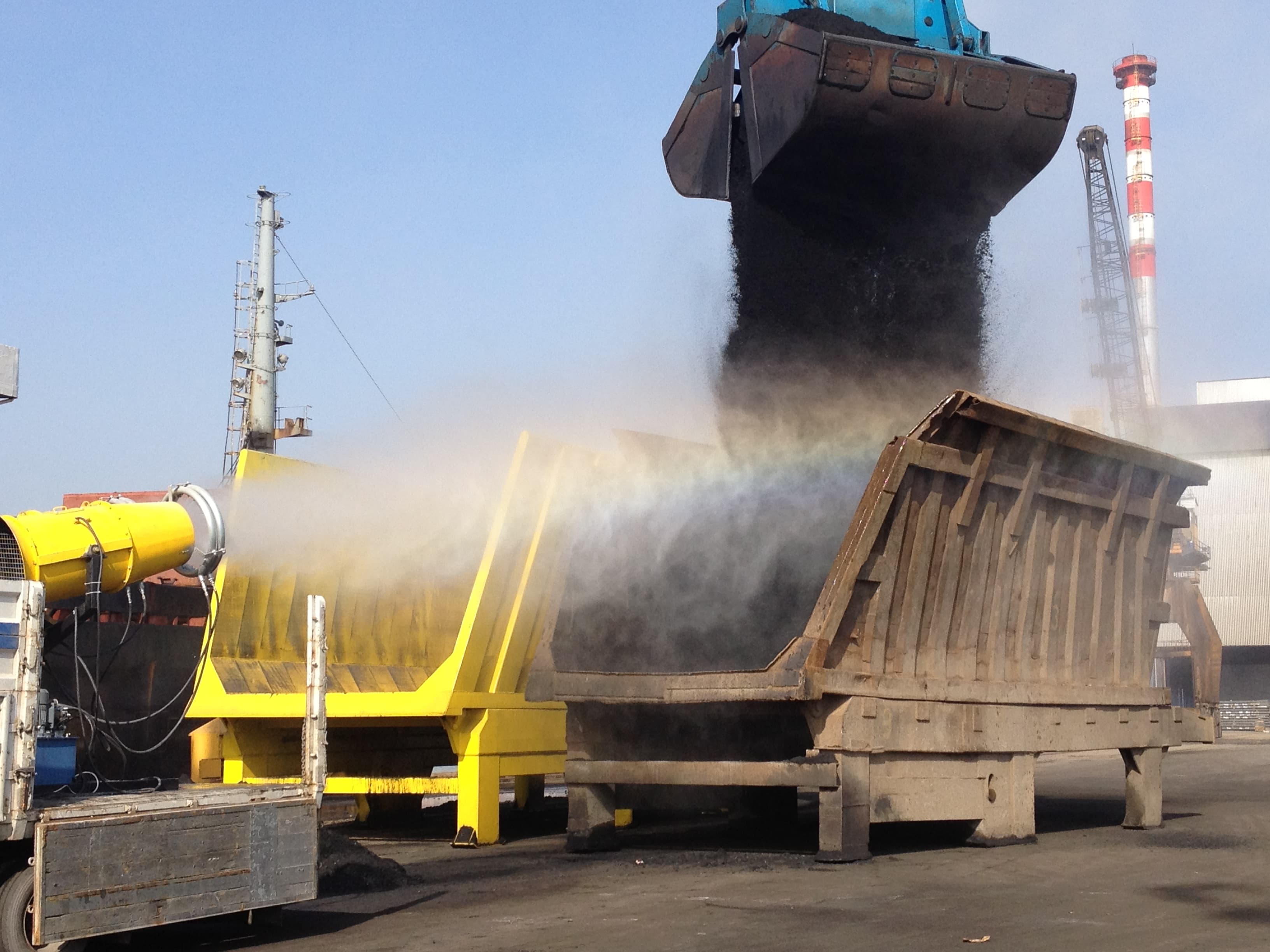 A fog cannon suppressing dust during the unloading of bulk material from a ship.