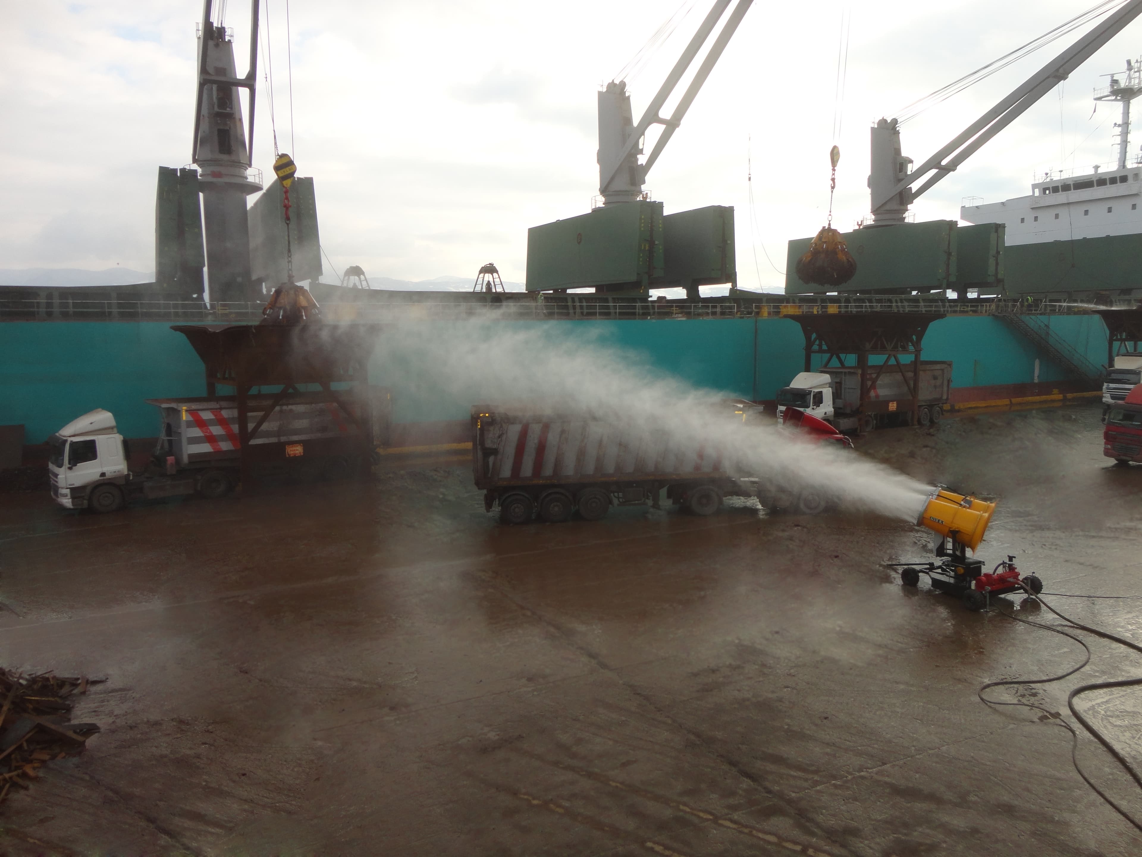 A fog cannon suppressing dust during the unloading of bulk material from a ship.